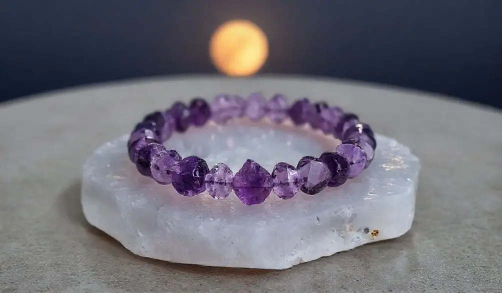 Amethyst Bracelet Meaning: Your Complete Guide to Peace, Intuition, and Spiritual Healing 2 - Buddha Bodhis An amethyst bracelet being cleansed and charged in the moonlight on a selenite plate.